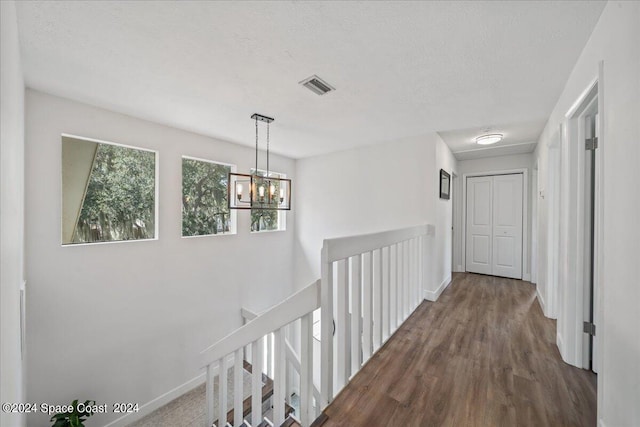 corridor featuring a textured ceiling, an inviting chandelier, and hardwood / wood-style flooring