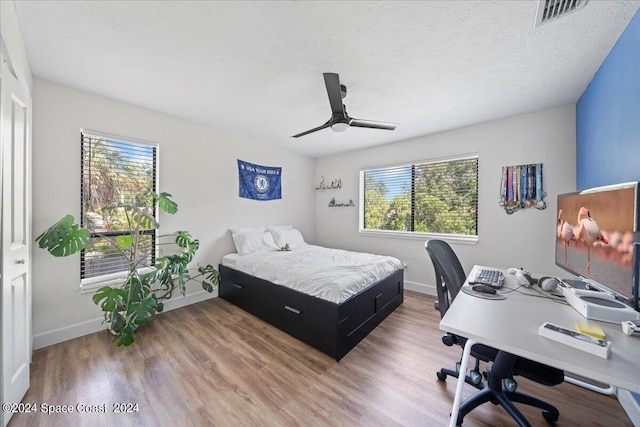 bedroom with hardwood / wood-style floors, ceiling fan, and a textured ceiling