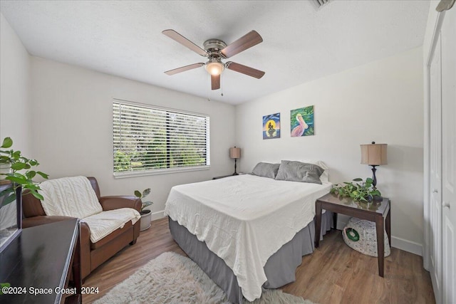 bedroom featuring a textured ceiling, hardwood / wood-style flooring, ceiling fan, and a closet