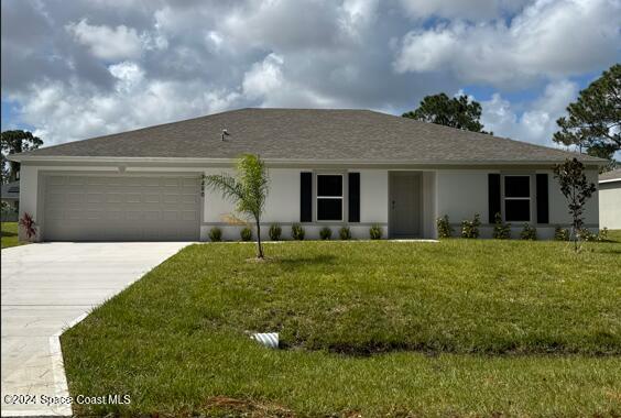 ranch-style house featuring an attached garage, concrete driveway, stucco siding, and a front yard