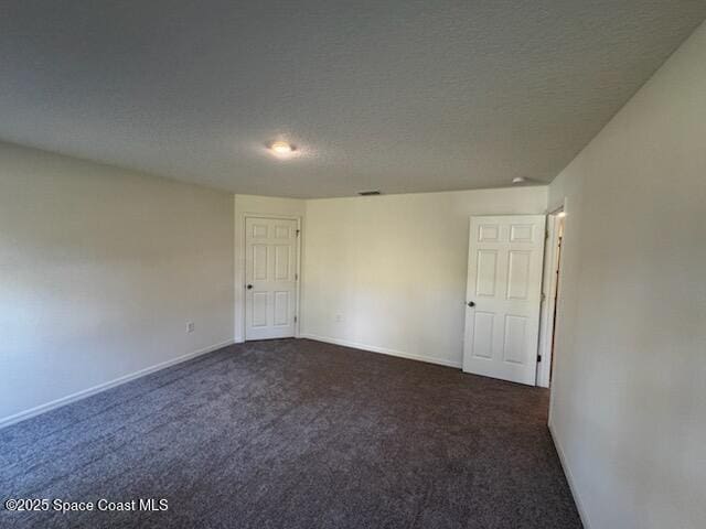 spare room with dark carpet and a textured ceiling