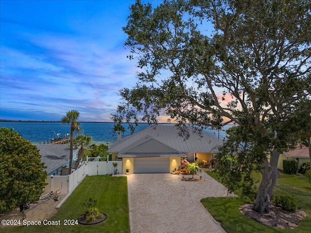 view of front of property with a water view, a garage, and a yard