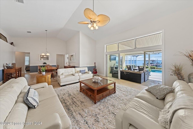 living room with ceiling fan with notable chandelier and high vaulted ceiling