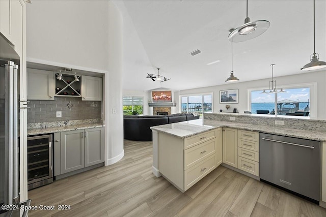 kitchen featuring light hardwood / wood-style flooring, appliances with stainless steel finishes, lofted ceiling, beverage cooler, and pendant lighting