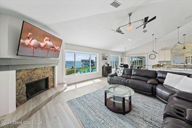 living room with light wood-type flooring, lofted ceiling, and a fireplace