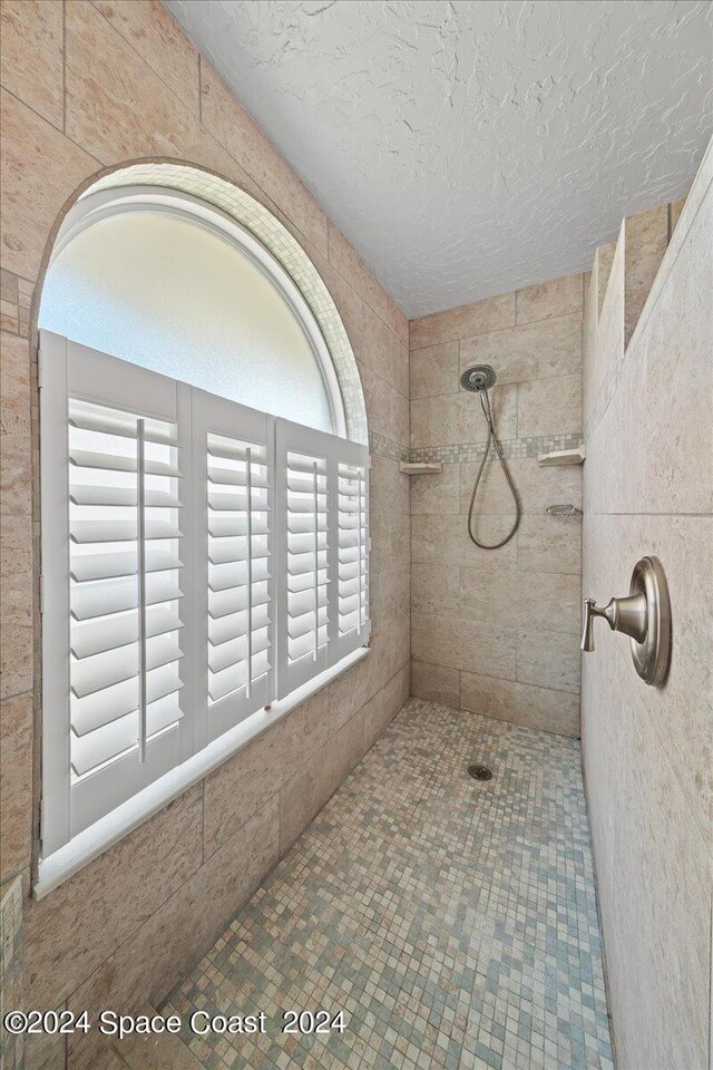 bathroom with tiled shower and a textured ceiling