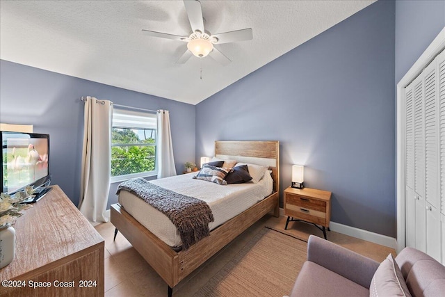 bedroom with a closet, ceiling fan, vaulted ceiling, and a textured ceiling