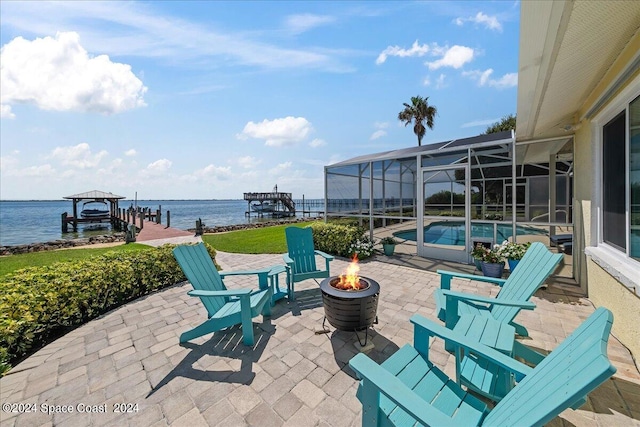 view of patio / terrace with a water view, glass enclosure, a fire pit, and a boat dock