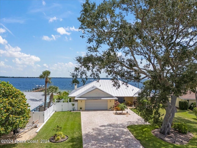 view of front facade with a garage, a water view, and a front lawn