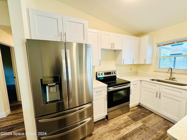 kitchen featuring stainless steel appliances, white cabinetry, vaulted ceiling, and sink