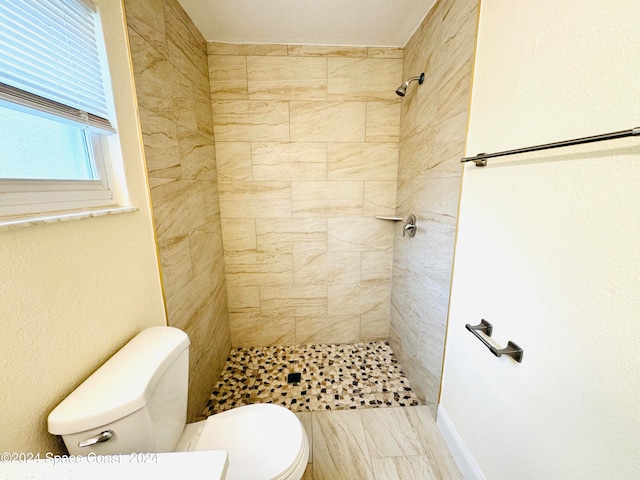 bathroom featuring a tile shower and toilet