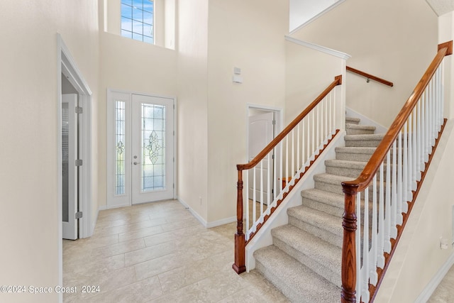 foyer featuring light tile patterned flooring, a towering ceiling, and a wealth of natural light