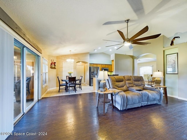 living room with ceiling fan, lofted ceiling, and dark wood-type flooring