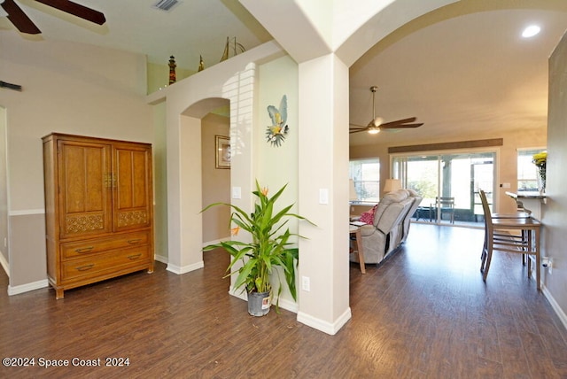 hallway with high vaulted ceiling and dark wood-type flooring