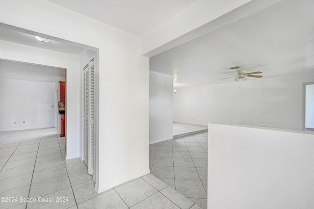 hallway with baseboards, visible vents, and light tile patterned floors