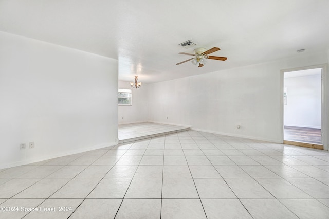 tiled empty room with ceiling fan with notable chandelier