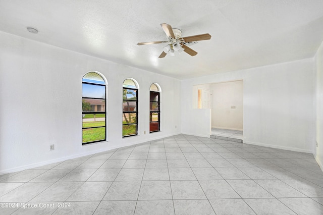 unfurnished room featuring a textured ceiling, light tile patterned floors, and ceiling fan