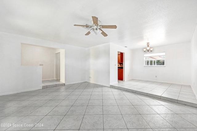 unfurnished room with ceiling fan with notable chandelier, a textured ceiling, and light tile patterned floors