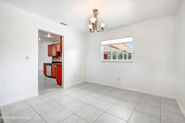 spare room with a chandelier and light tile patterned floors