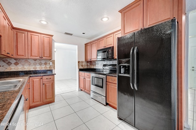 kitchen featuring tasteful backsplash, light tile patterned floors, a textured ceiling, black appliances, and sink