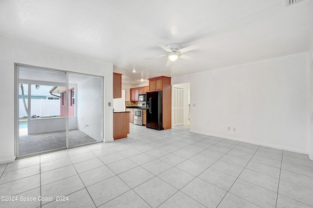 interior space with ceiling fan, black fridge, light tile patterned flooring, and stainless steel stove