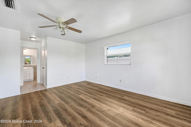 spare room with baseboards, visible vents, wood finished floors, and a ceiling fan