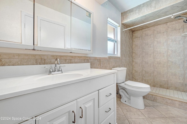 full bath featuring tile walls, a tile shower, toilet, and vanity