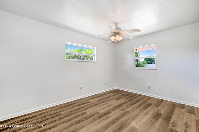 empty room featuring a wealth of natural light, ceiling fan, hardwood / wood-style floors, and a textured ceiling