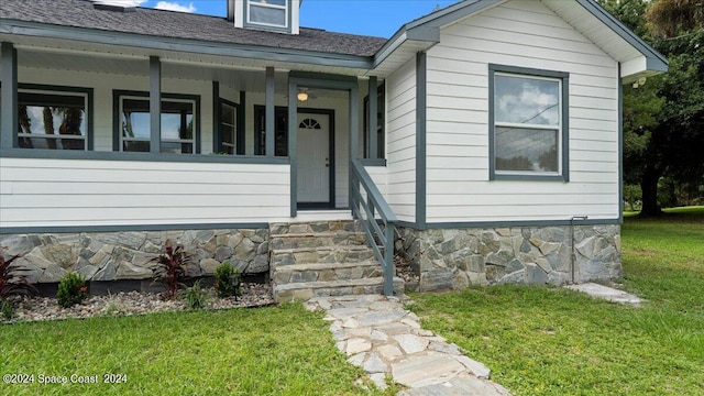 property entrance with a yard and covered porch