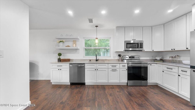 kitchen featuring decorative light fixtures, dark wood-type flooring, stainless steel appliances, sink, and white cabinets