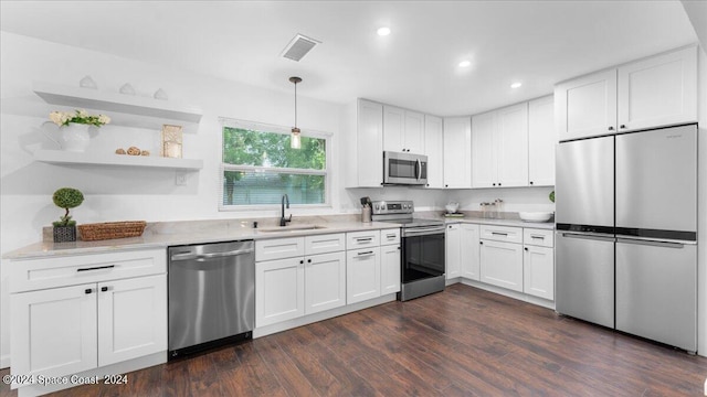 kitchen with decorative light fixtures, white cabinets, appliances with stainless steel finishes, and sink