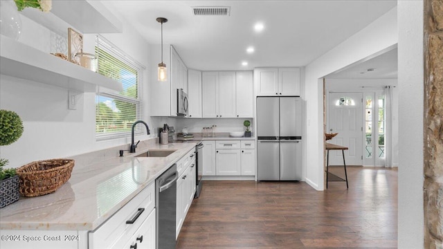 kitchen with stainless steel appliances, sink, white cabinetry, a wealth of natural light, and light stone counters