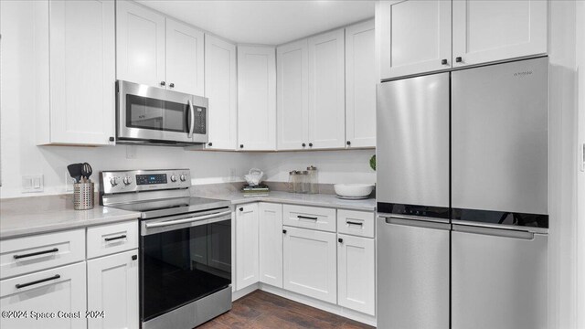 kitchen featuring appliances with stainless steel finishes, white cabinetry, and dark hardwood / wood-style floors