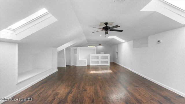 bonus room with ceiling fan, dark hardwood / wood-style floors, and lofted ceiling with skylight