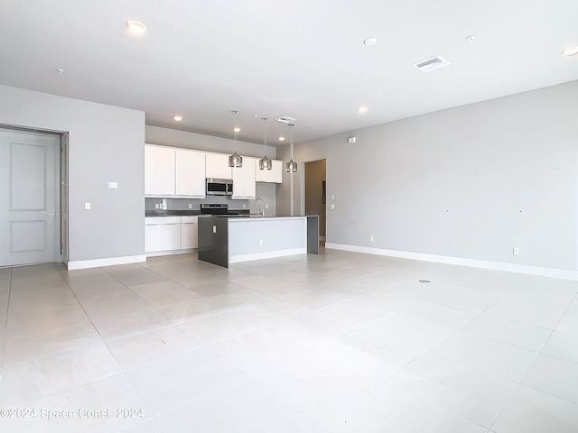 kitchen featuring white cabinets, decorative light fixtures, appliances with stainless steel finishes, light tile patterned flooring, and a kitchen island with sink