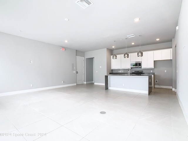 kitchen featuring pendant lighting, light tile patterned floors, a kitchen island with sink, stove, and white cabinets