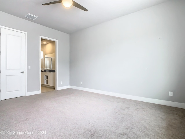 unfurnished bedroom with ceiling fan, ensuite bath, and carpet floors