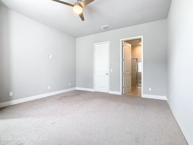 unfurnished bedroom featuring light colored carpet, connected bathroom, and ceiling fan