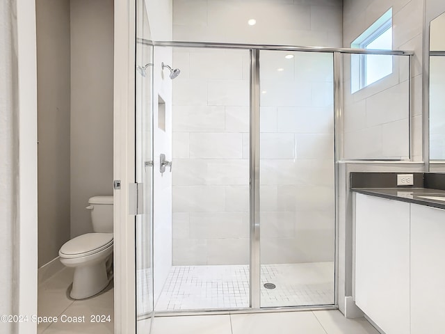 bathroom featuring tile patterned flooring, walk in shower, toilet, and vanity