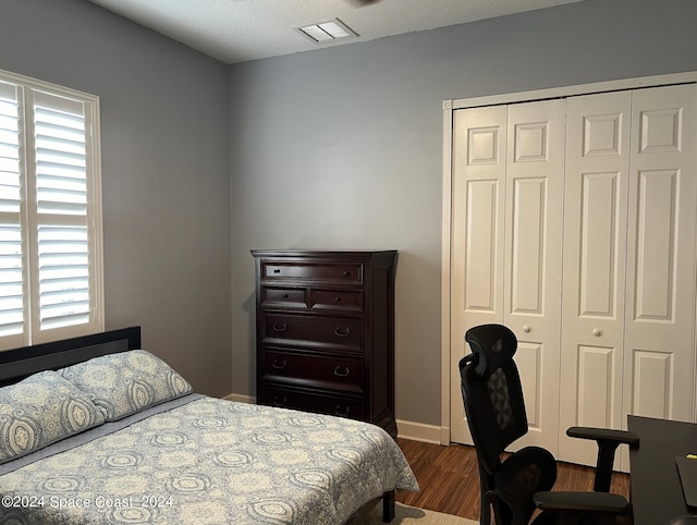 bedroom with dark hardwood / wood-style flooring, multiple windows, and a closet