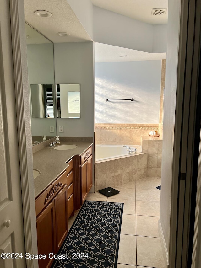 bathroom featuring a relaxing tiled tub, tile patterned floors, vanity, and a textured ceiling