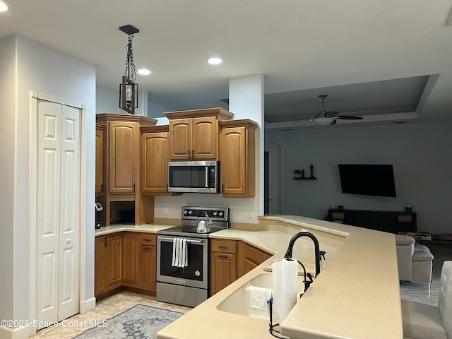 kitchen with sink, ceiling fan, stainless steel appliances, decorative light fixtures, and kitchen peninsula