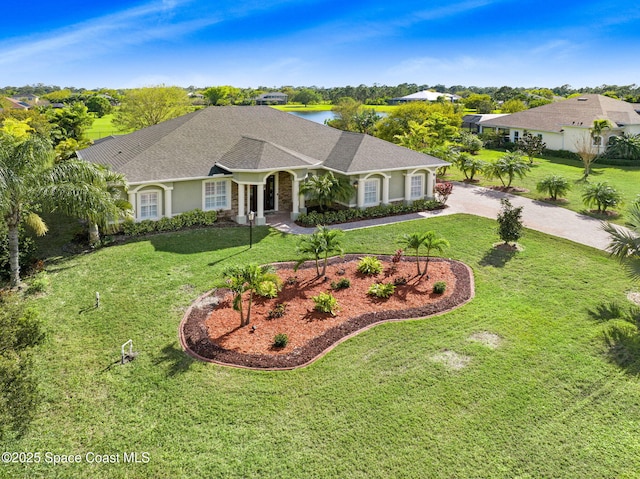 view of front of home with driveway, roof with shingles, a front yard, and stucco siding