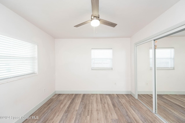 unfurnished bedroom featuring a closet, multiple windows, and light wood-type flooring