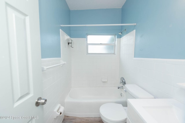 bathroom featuring tiled shower / bath, tile walls, hardwood / wood-style floors, and toilet