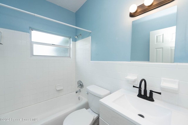 full bathroom featuring toilet, tiled shower / bath, vanity, and tile walls