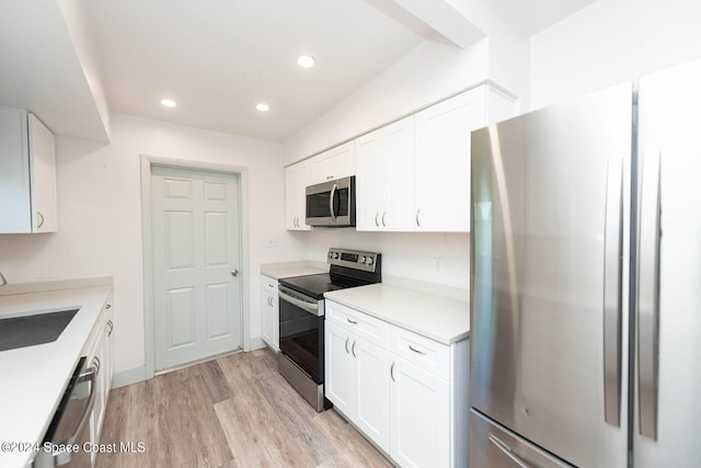 kitchen featuring appliances with stainless steel finishes, white cabinets, sink, and light wood-type flooring