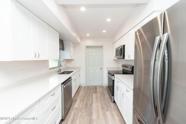 kitchen featuring white cabinetry, stainless steel appliances, sink, and light wood-type flooring