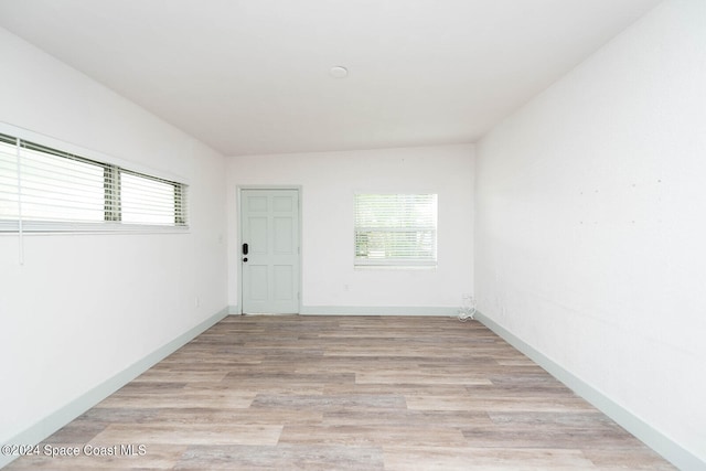 spare room with lofted ceiling and light hardwood / wood-style floors