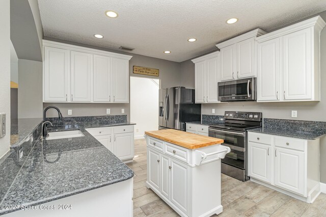 kitchen with kitchen peninsula, sink, stainless steel appliances, and white cabinets